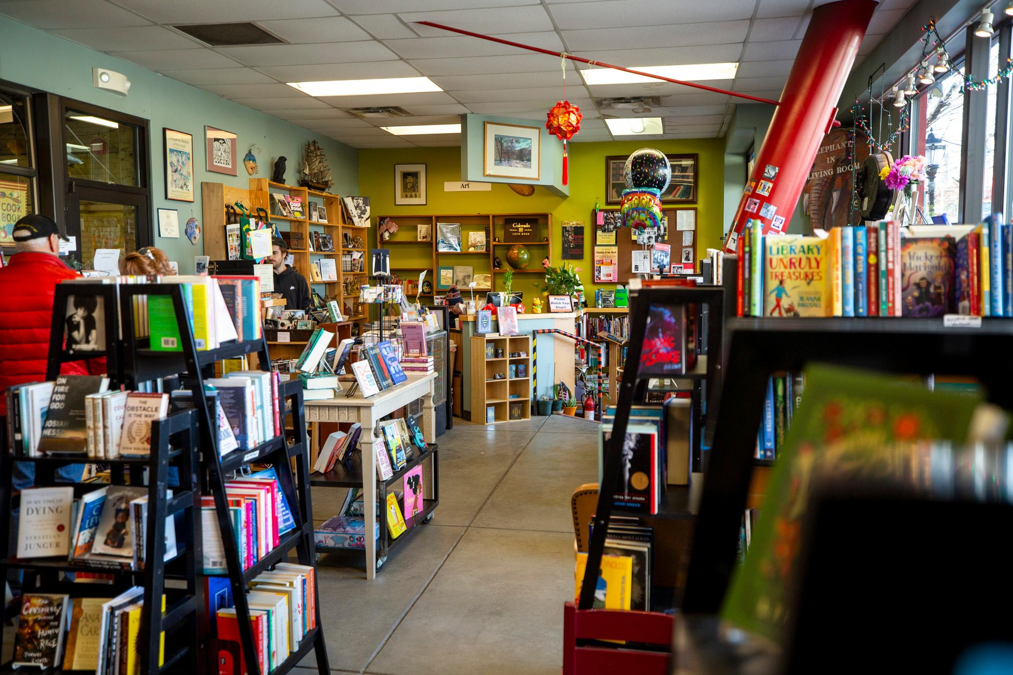 A cluttered bookstore with walls of teal and green. There are books everywhere.