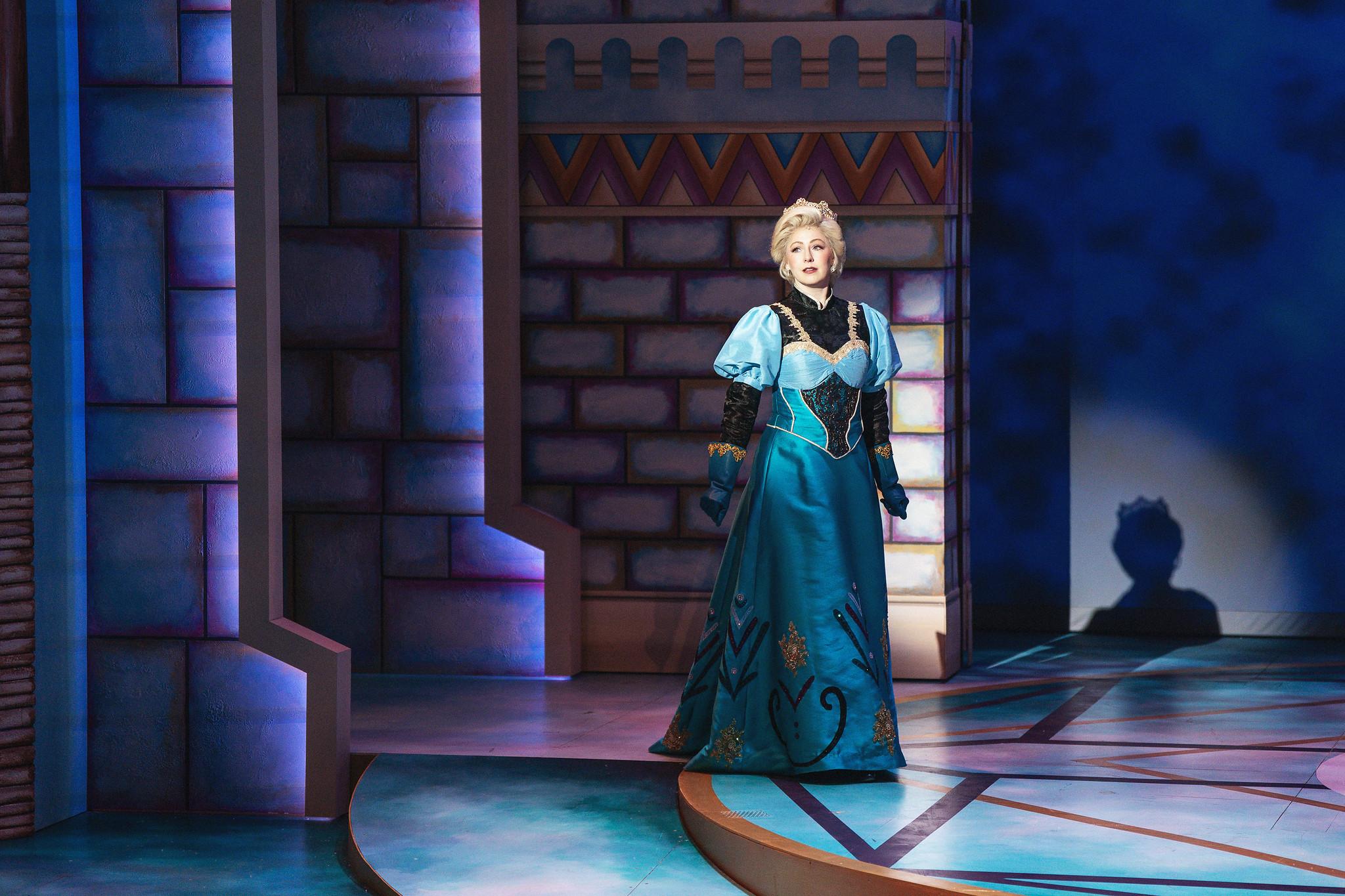 Woman is blue Queen Elsa dress strides onto stage.