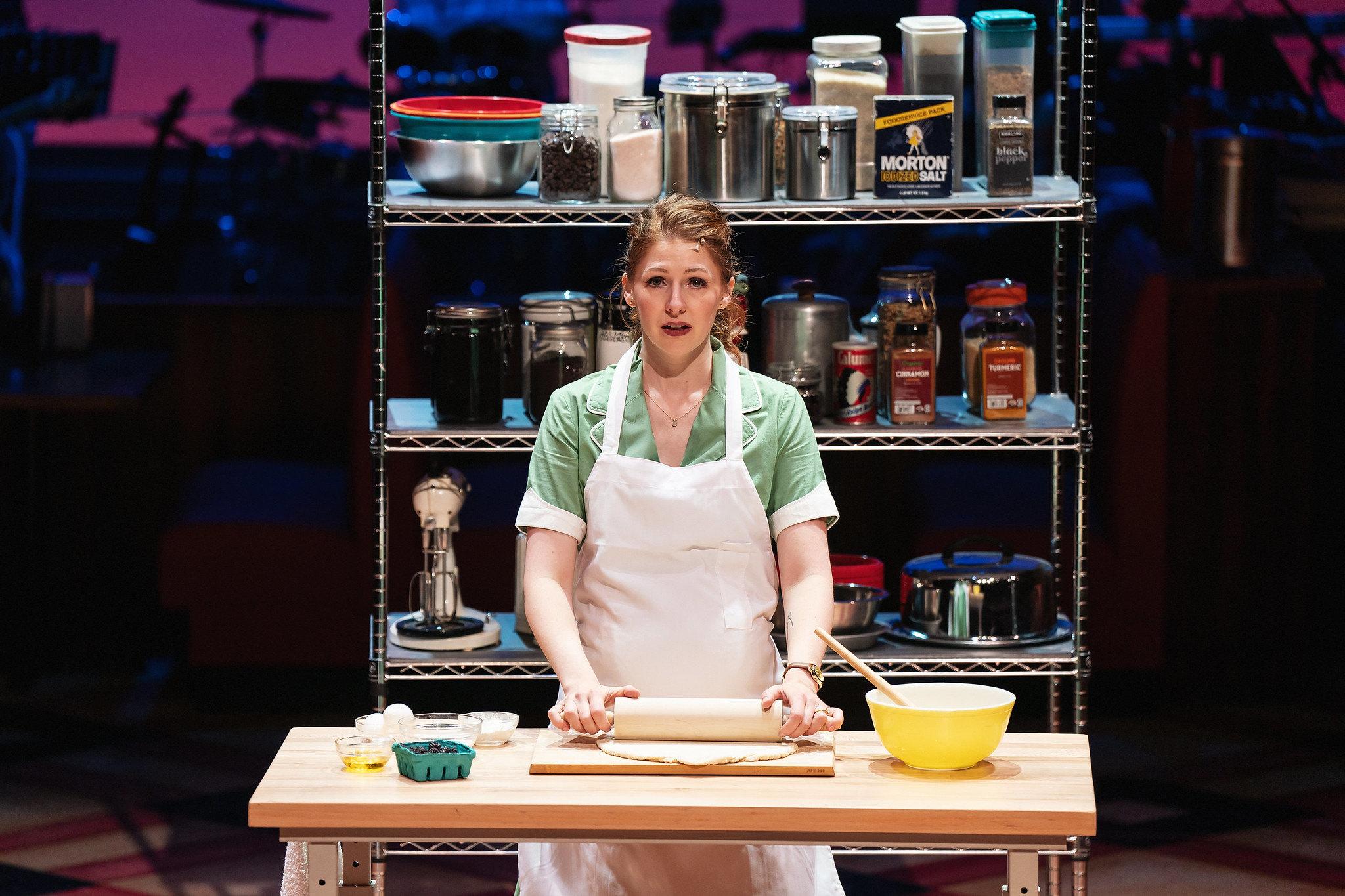 Waitress baking a pie looks into camera with a sad expression.