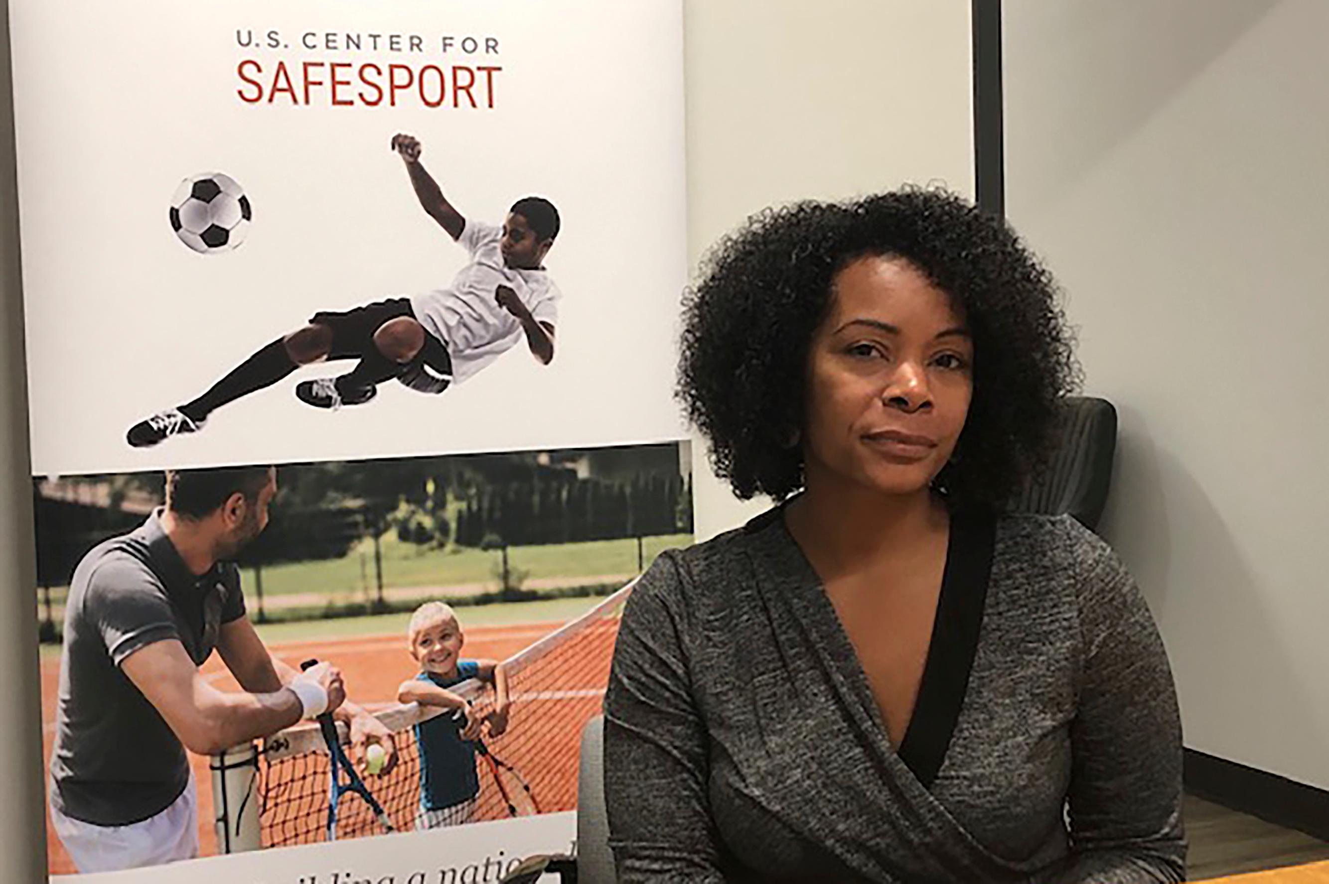 Ju'Riese Colon, the CEO for the U.S. Center for SafeSport, poses in front of a U.S. Center for SafeSport poster.