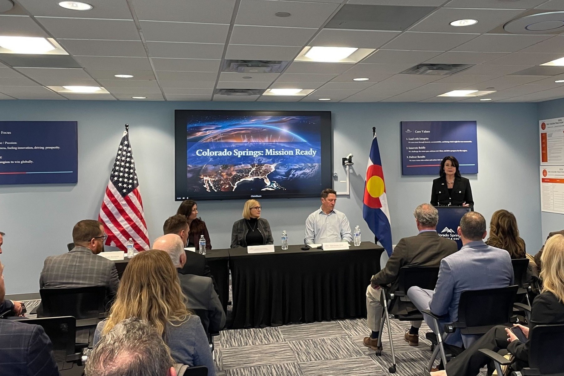 People sit in a audience facing a panel of city officials.