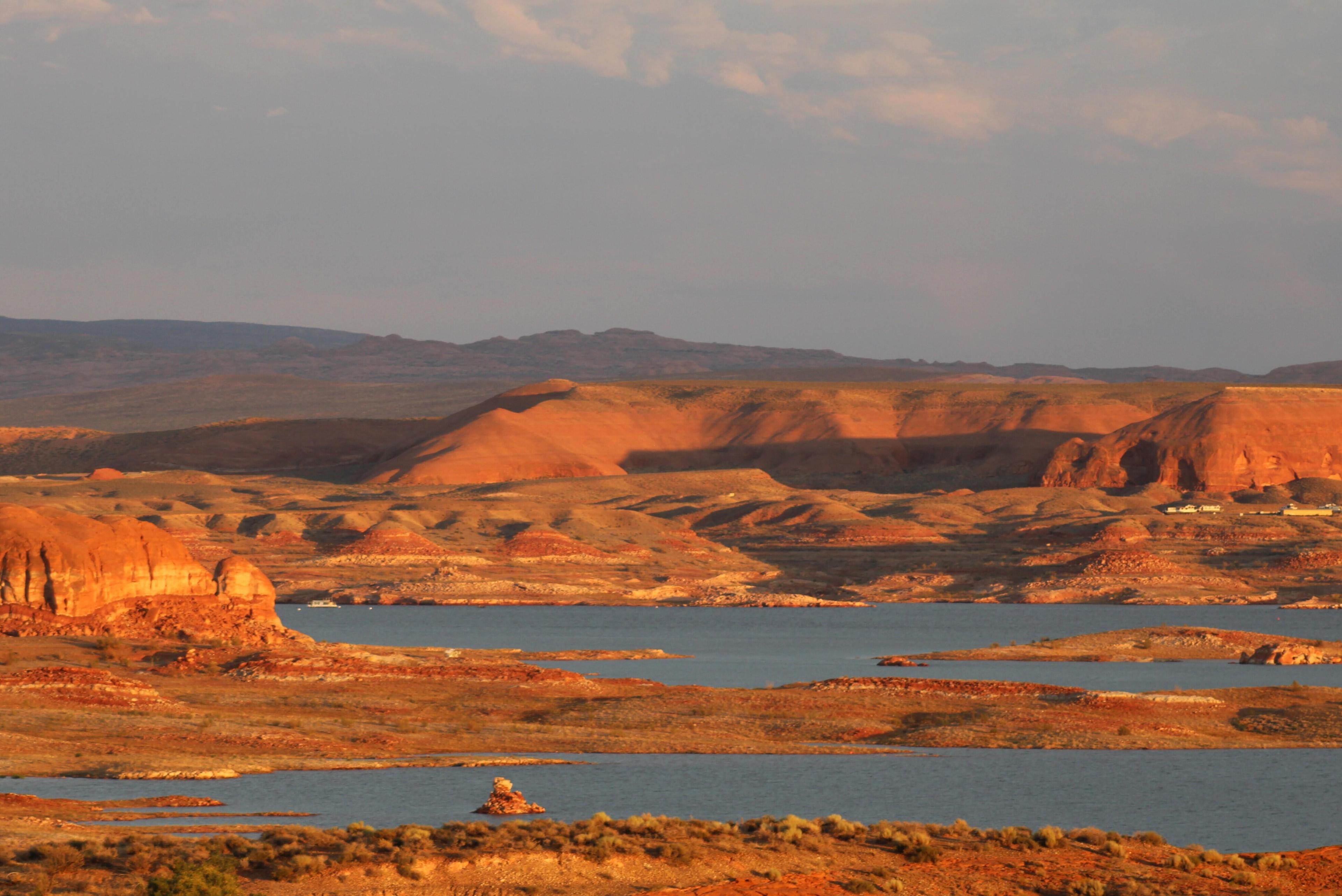 A low reservoir flows between desert rock while the sunset turns the landscape orange