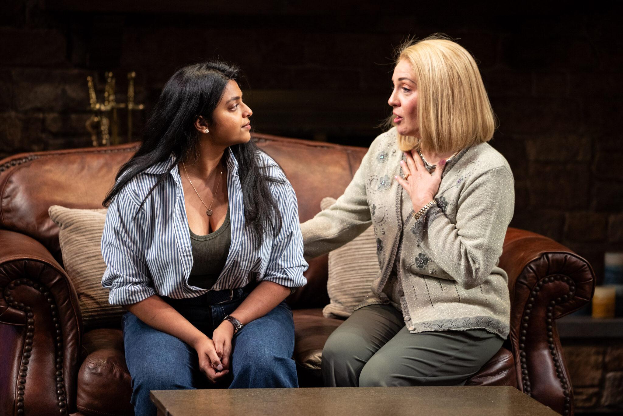 Two women, one younger and one older, sit on a couch talking.