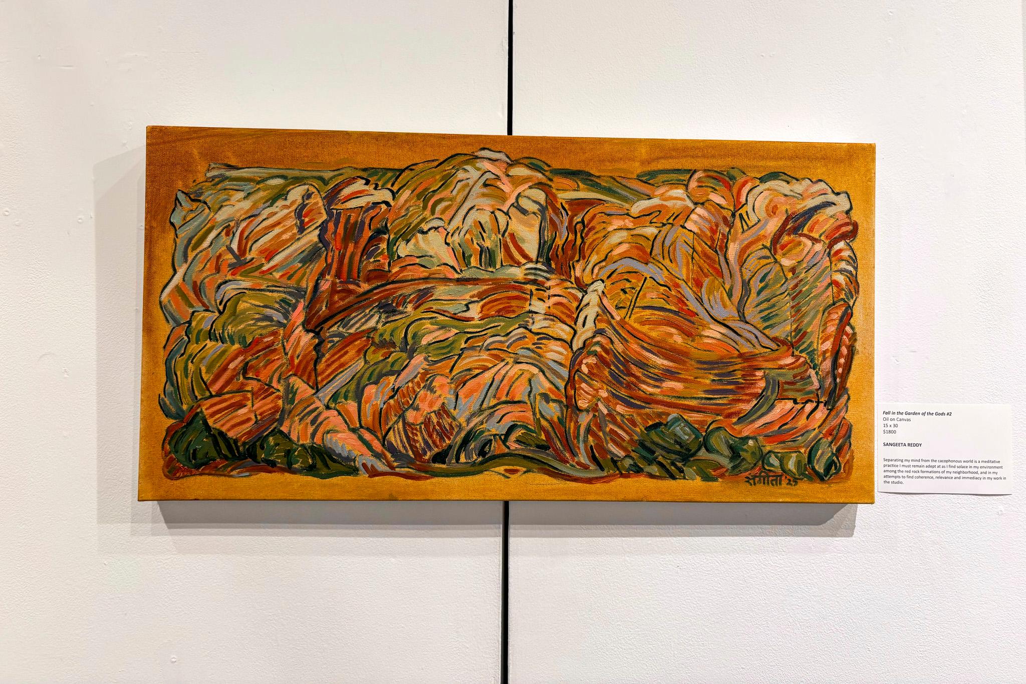 A painting of ochre and swirls, reminiscent of a landscape, is mounted to a white wall.