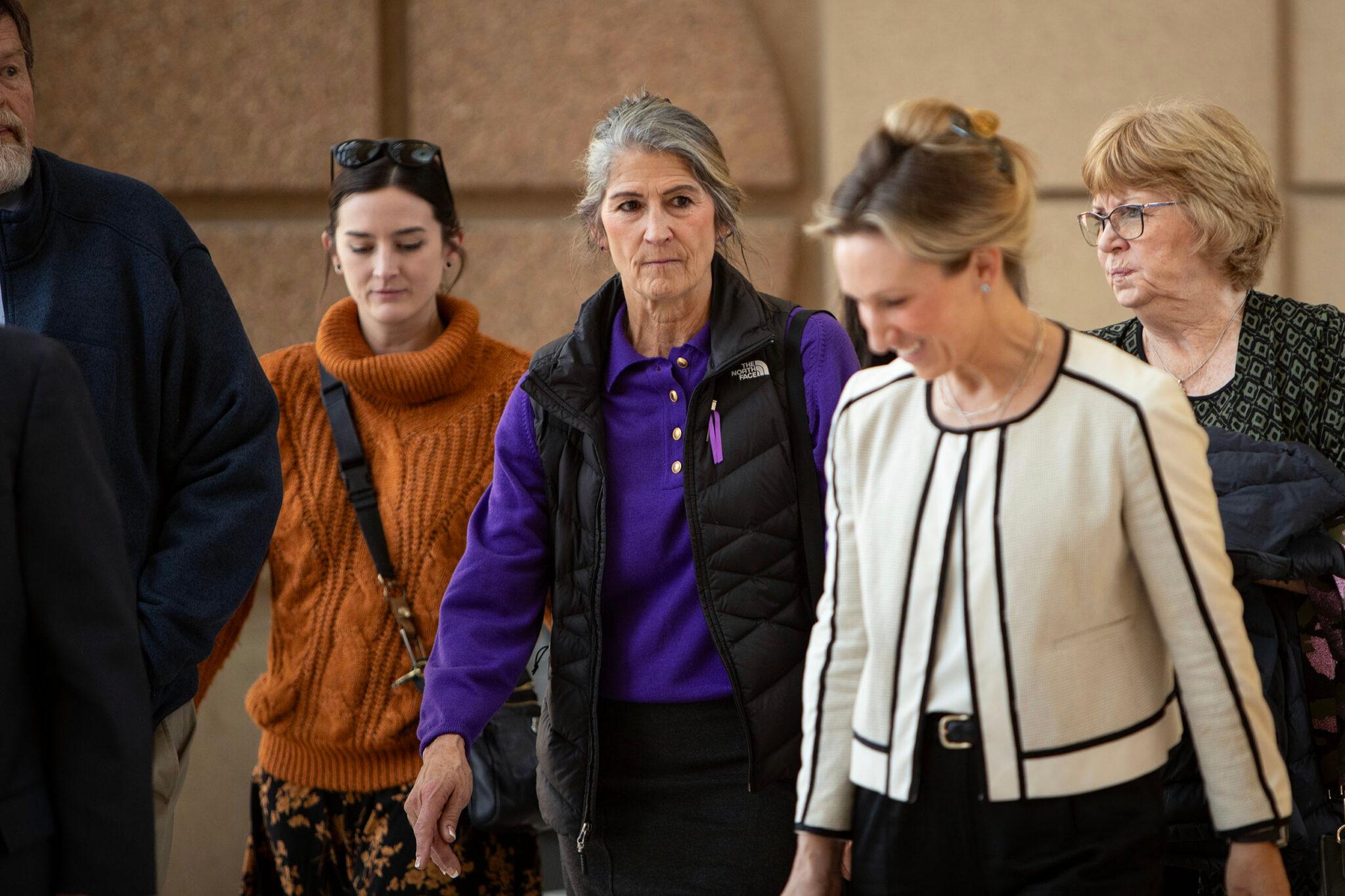 A group of women walk through a warmly lit chamber.