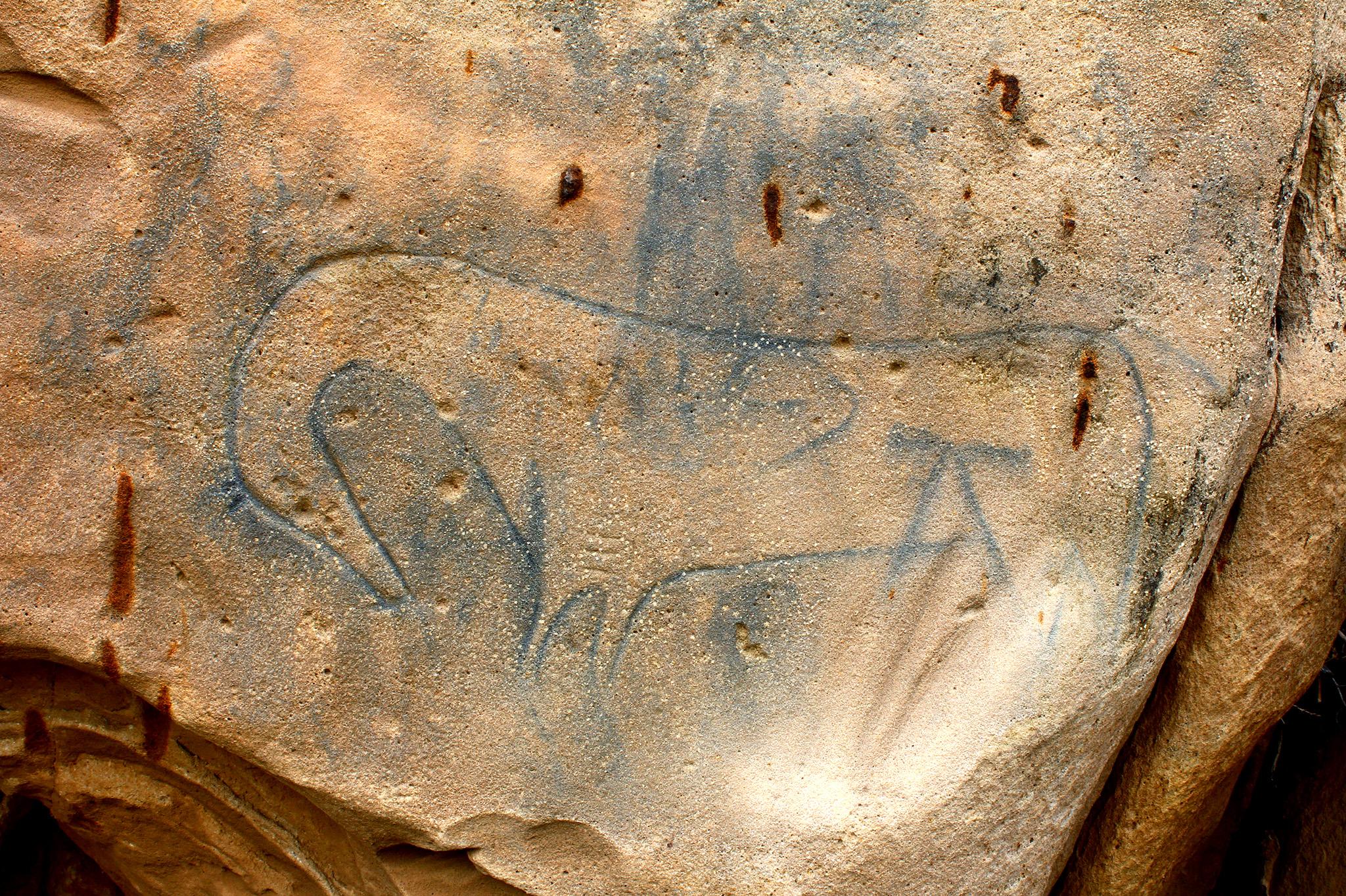 The image features a rock with a stylized line drawing of a horse on it.
