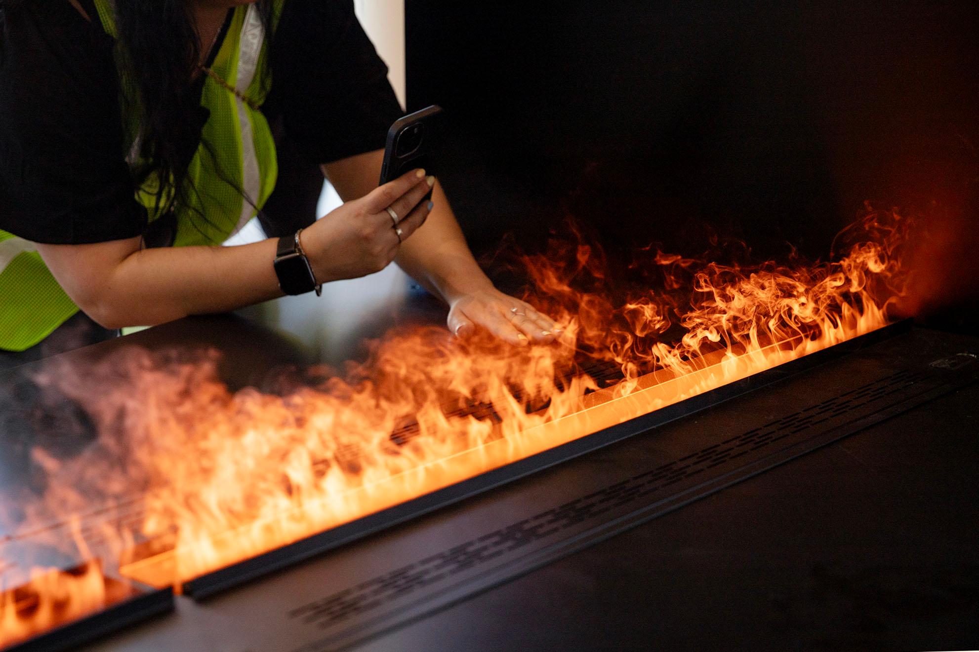 A hand touches a cloud of vapor that glows orange from lights below.