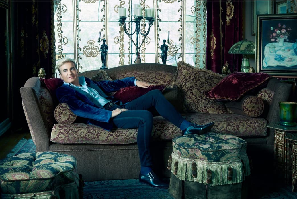 In a promotional photo, Jean-Yves Thibaudet lies on a couch in a blue suit.