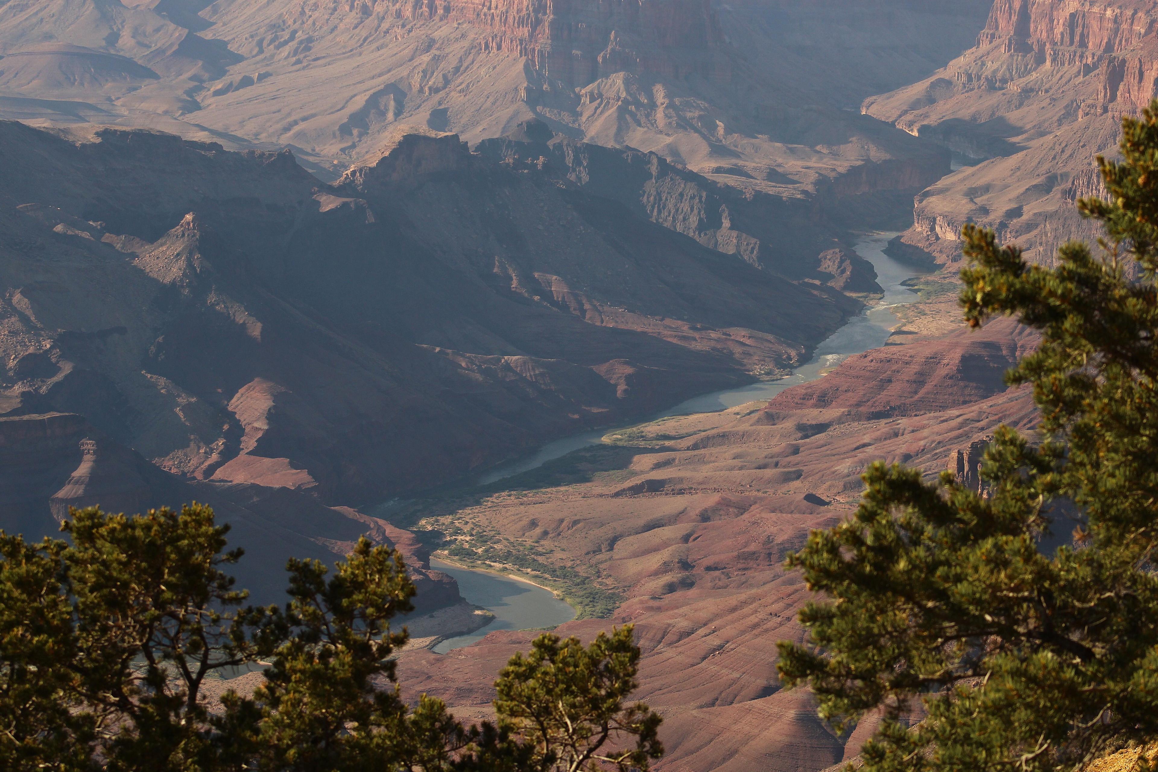 A blue river flows through a large, rocky desert canyon